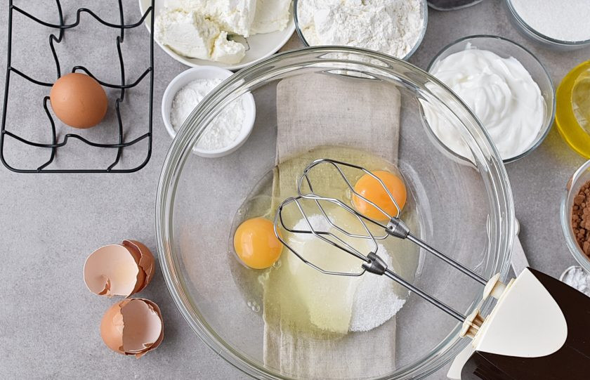 1. Этап. Шоколадный пирог с творогом: Включите духовку на разогрев до 170 градусов. Взбейте два яйца с половиной сахара в пышную пену.