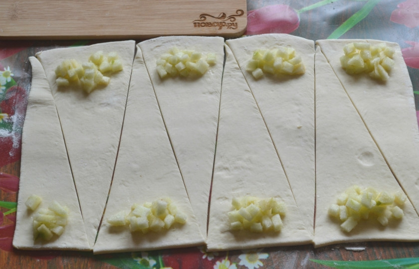 1. Этап. Круассаны из готового слоеного теста: На каждый треугольник положите немного начинки. Количество начинки зависит от ваших предпочтений. Для меня в круассанах главное мягкое и очень вкусное тесто, поэтому яблок я кладу совсем немного.
