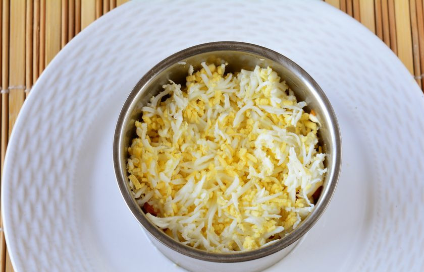 1. Этап. Селедка под шубой по ГОСТу: Почистите куриные яйца и натрите следующим слоем в салат. Посолите немного и полейте майонезом.