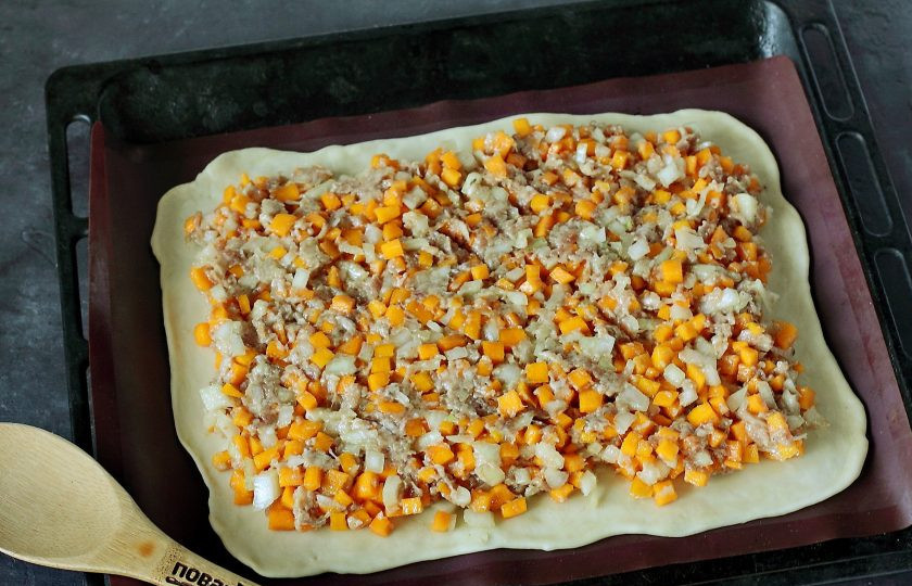 1. Этап. Пирог с тыквой и мясом: Тесто разделите на две части. Каждую часть раскатайте по размеру вашего противня, толщиной примерно 3 мл. Положите один пласт и распределите на нем равномерно всю начинку, немного отступив от краев.