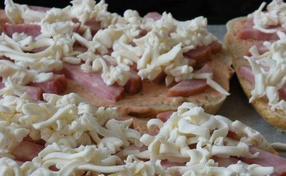 1. Этап. Пицца на хлебе: В завершение посыпьте ветчину тертым плавленым сыром. Положите хлеб на противень и поставьте его в духовку, разогретую до двухсот градусов. Выпекайте пиццу десять-пятнадцать минут. При подаче посыпьте рубленой зеленью.