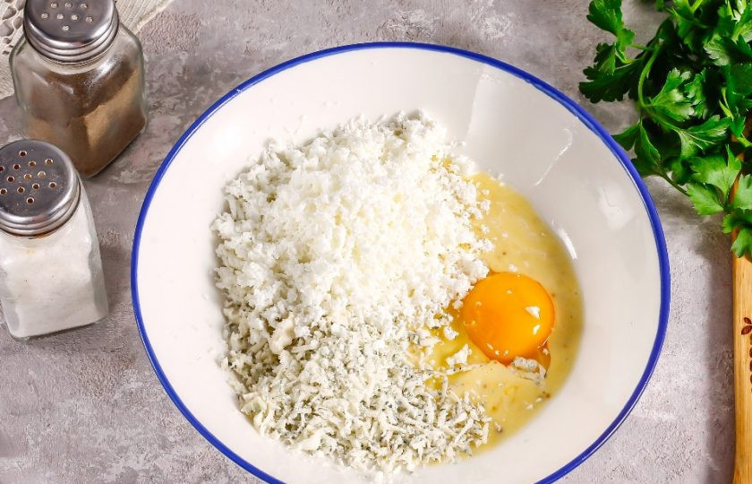 1. Этап. Сырный пирог: Выложите в глубокую емкость майонез или замените его на сметану. Вбейте туда же куриное яйцо, натрите на терке с мелкими ячейками три вида сыра, оставляя немного для присыпки в конце — примерно 30 грамм, и все тщательно перемешайте. Если сыр 