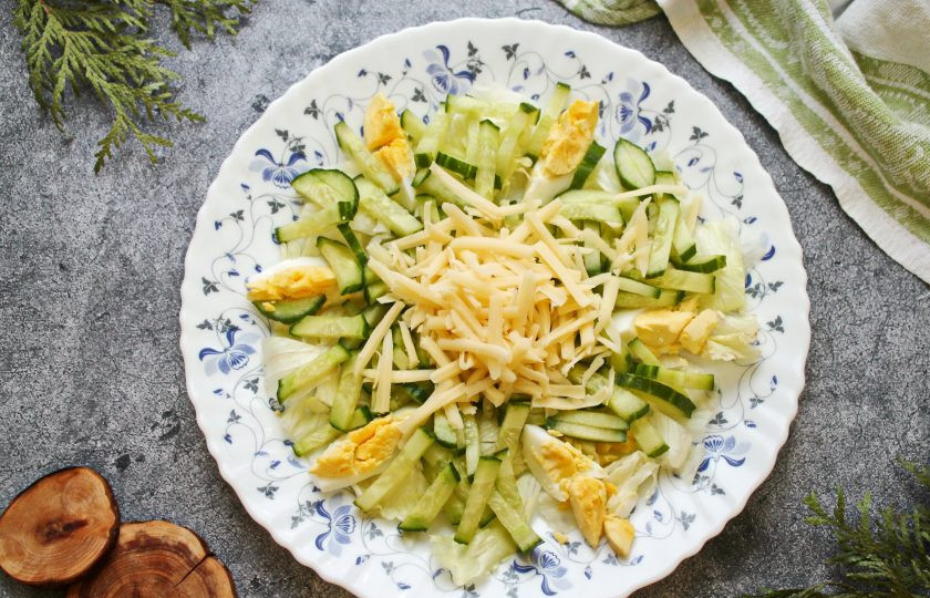 1. Этап. Салат из копченой сельди с сыром: Огурец порежьте крупной соломкой, сыр натрите на крупной терке. Выложите огурец и сыр в салат.