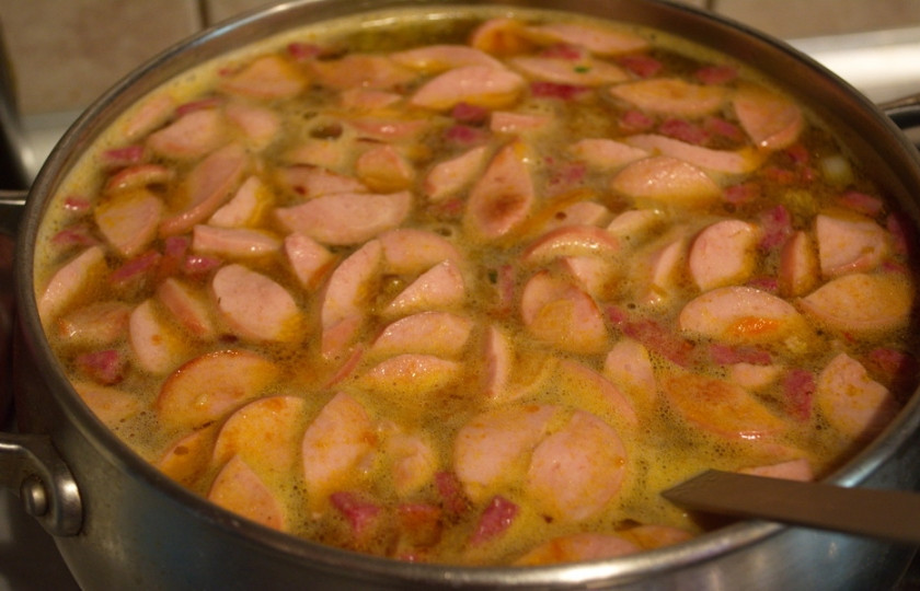 1. Этап. Солянка с сосисками: В кастрюле вскипятите воду. Когда она закипит добавьте овощной соус и обжаренные копчености.