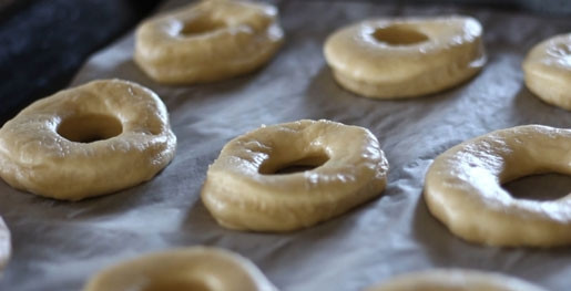 1. Этап. Пончики печеные: 7. Небольшими кусочками раскатайте коржи. Из каждого двумя видами стаканов выдавите формочки печенья в виде бублика. Переложите пончики на противень, дайте подняться полчаса. Выпекайте при 180 С до изменения цвета.