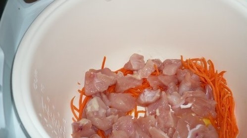 1. Этап. Куриная грудка с морковью: 3. Когда морковь пустит сок, выложите в чашу кусочки грудки курицы. Начистите чеснок. Каждый зубчик разрежьте пополам. Добавьте к куриному филе. Посолите.