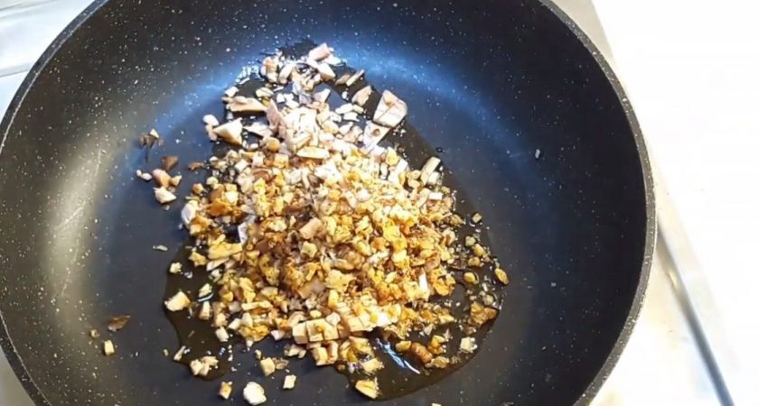 1. Этап. Грибы, фаршированные орехами и сыром: 4. На оливковом масле обжарьте измельченные с орехами в течение 4-5 минут (обязательно посолите). Высыпьте орехи с грибами в мисочку с сыром. Нафаршируйте шапочки грибов с помощью ложки, наложив начинки с горкой, так как сыр немного растает и уменьшится.