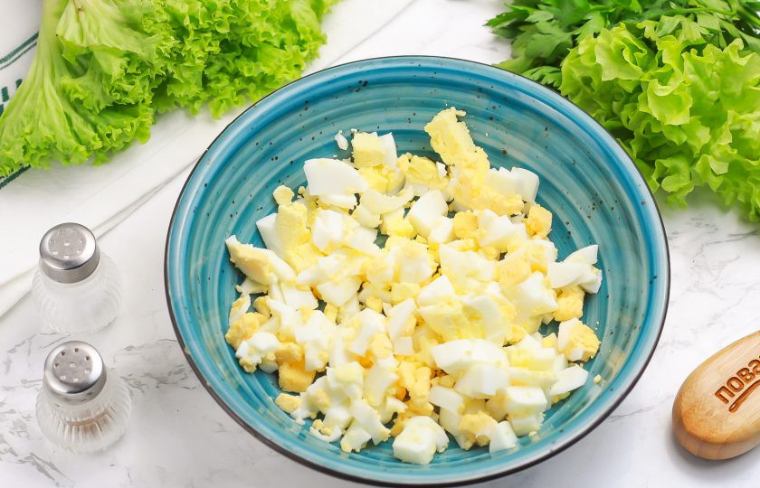 1. Этап. Салат с огурцом, сыром и тунцом: Очистите скорлупу с отварных яиц, промойте их в воде и нарежьте мелким кубиком. Высыпьте нарезку в салатник или глубокую миску.