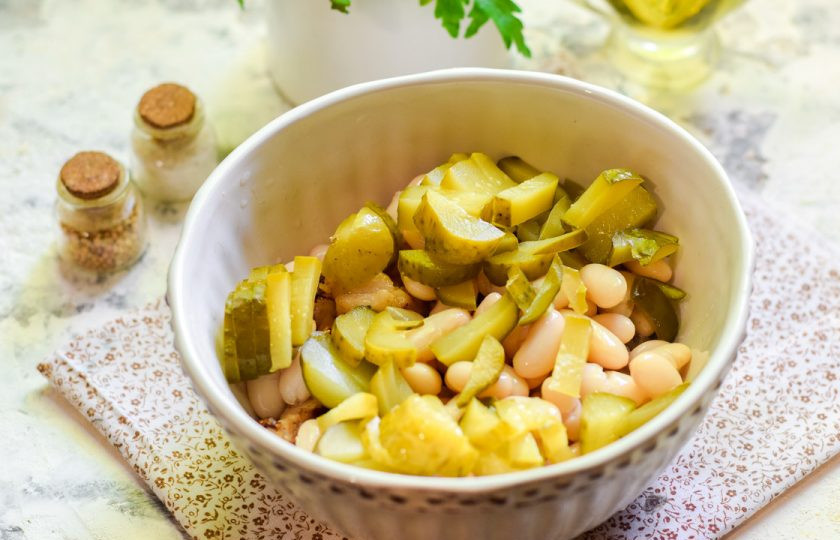 1. Этап. Салат Василиса с фасолью: Огурцы маринованные нарежьте полосками, добавьте в салат.