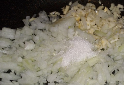 1. Этап. Запеченная скумбрия с овощами и сыром: Сковороду ставим на огонь. Наливаем в нее растительное масло. Выкладываем нарезанный лук и чеснок. Добавляем сахар. Обжариваем овощи 5 минут.