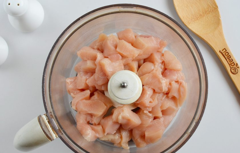 1. Этап. Закусочный торт для мужчин: Куриное филе порежьте маленькими кусочками, выложите в чашу комбайна и измельчите до тех пор, пока масса не станет однородной.