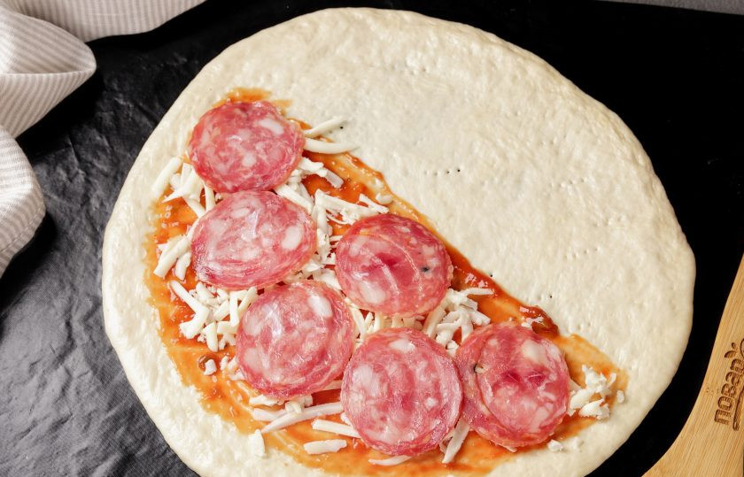 1. Этап. Пицца Кальцоне: На сыр выложите нарезанную тонкими слайсами колбасу.