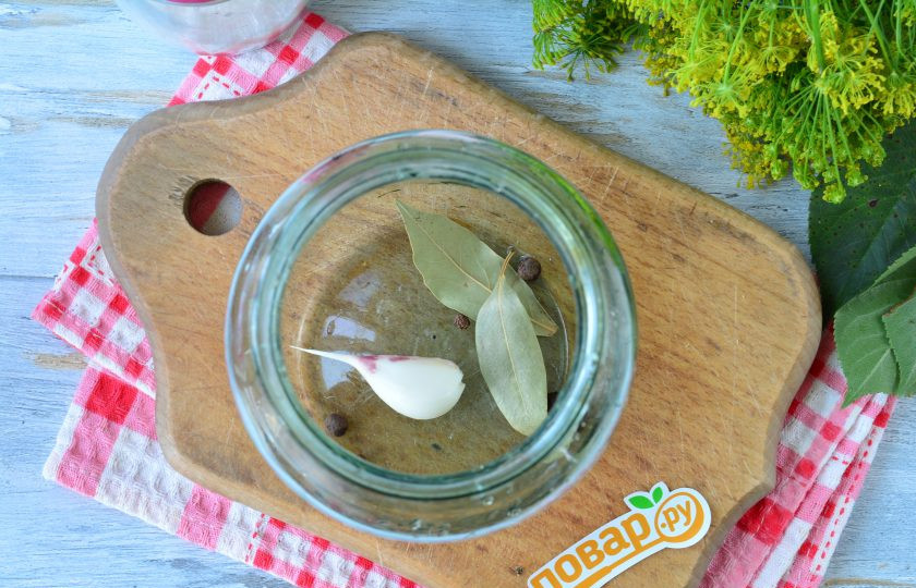 1. Этап. Маринованные огурцы Детские: На дно чистой простерилизованной банки выложите специи: чеснок, перец горошком и лавровый лист.