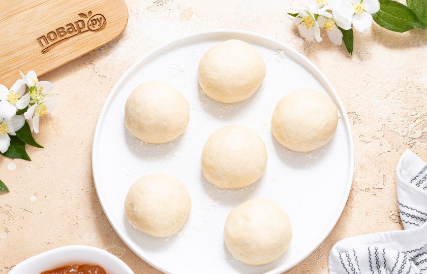 1. Этап. Постные пирожки с повидлом: Поднявшееся тесто разделите на порционные кусочки примерно по 40-50 грамм. Скатайте их в шарики, накройте полотенцем и дайте им 10 минут расстояться.