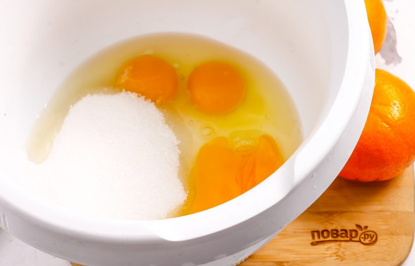 1. Этап. Бисквит с мандаринами: Куриные яйца вбейте в чашу кухонного комбайна или в глубокую емкость. Всыпьте туда же сахарный песок и соль. Соль добавлять обязательно — она подчеркнет сладость десерта!