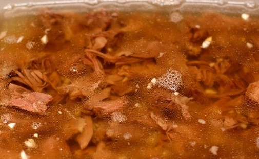 1. Этап. Холодец из бульонки говяжьей: 6. Если не хотите, чтобы застывший холодец был с жиром, в процессе варки снимайте образовавшийся жир на поверхности бульона. Заливаем мясо теплым бульоном, добавляем мелко нарезанный чеснок, даем полностью остыть на столе. Затем отправляем в холодильник до полного застывания. На 3 л воды нам понадобится 2 столовые ложки желатина.