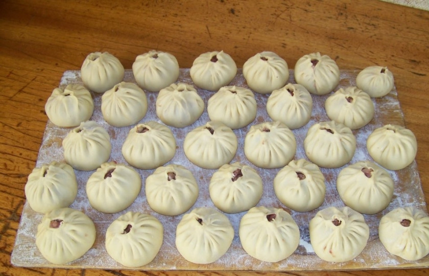 1. Этап. Бурятские бузы: Осталось уложить начинку на вырезанное тесто и аккуратно защипнуть будущие бузы, чтобы они приобрели правильную форму. Тесто нужно собрать кулёчком над мясом, но так, чтобы мясо не было полностью закрыто. Края теста нужно защипнуть и уложить защипы в одном направлении. В итоге получится форма, напоминающая бутон цветка.