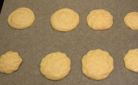 1. Этап. Печенье Аврора: Противень застелите пергаментом, смажьте его маслом. Переложите тесто в кондитерский мешок или полиэтиленовый пакет с небольшим надрезом. Выдавите печенье на противень.