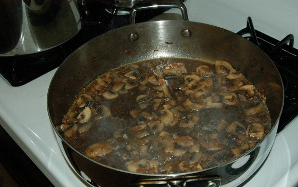 1. Этап. Бефстроганов с грибами и луком: Добавьте бульон и коньяк в сковороду. Жидкость должна слегка покрыть грибочки. Тушите в течении 15 минут. В это время можно заняться лапшой. Сварите её и добавьте 2 столовые ложки масла.