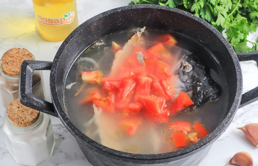 1. Этап. Уха из форели с рисом: Промойте помидор и вырежьте зеленую сердцевинку. Нарежьте крупными кусочками и добавьте в емкость. Отварите примерно 10 минут.