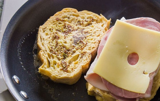 1. Этап. Монте-Кристо сэндвич с ветчиной: 3. Сковороду поставьте на огонь, растопите в ней сливочное масло. Выложите 2 ломтика хлеба. Один посыпьте семенами горчицы, на другой выложите ветчину и сыр.