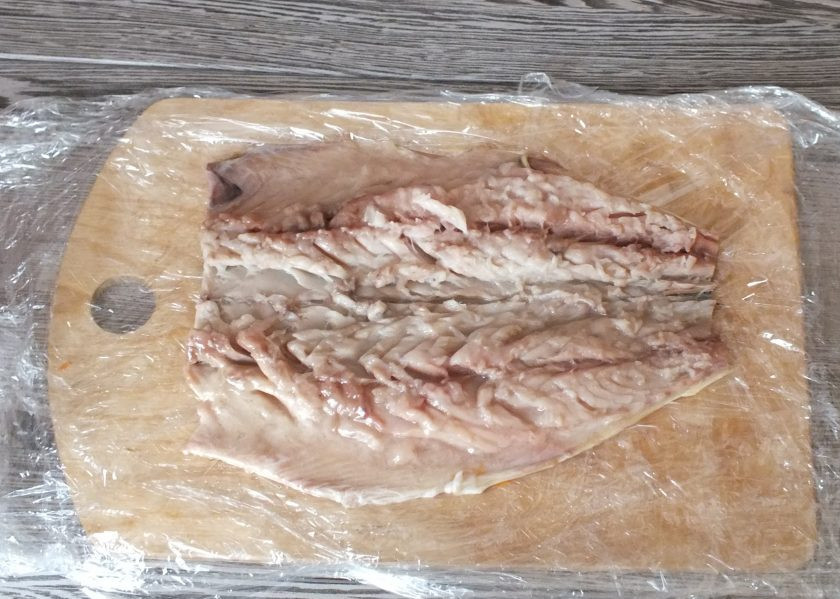 1. Этап. Скумбрия фаршированная с желатином и яйцом: Скумбрию вымойте, удалите голову, хвост, внутренности, все возможные кости. Доску застелите пищевой пленкой. Лучше если это будет несколько слоёв. Выложите на пленку подготовленную рыбу.