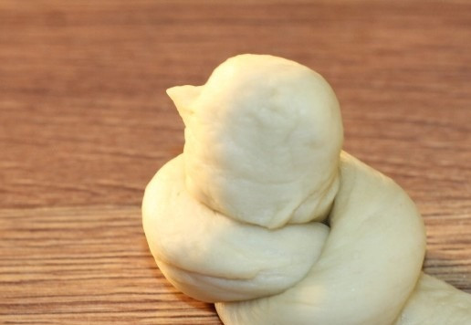 1. Этап. Булочки-птички Жаворонки: 14. Из кончиков узелка, формируем головку и хвостик жаворонка. На голове - вытягивая тесто лепим клюв. Кусочки изюма - это будут глазки жаворонка. На хвостике делаем надрезы.