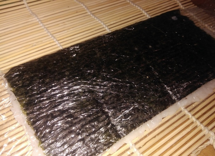 1. Этап. Роллы Аляска: 4. Аккуратно поднимите пленку и переверните нори, они окажутся вверху.