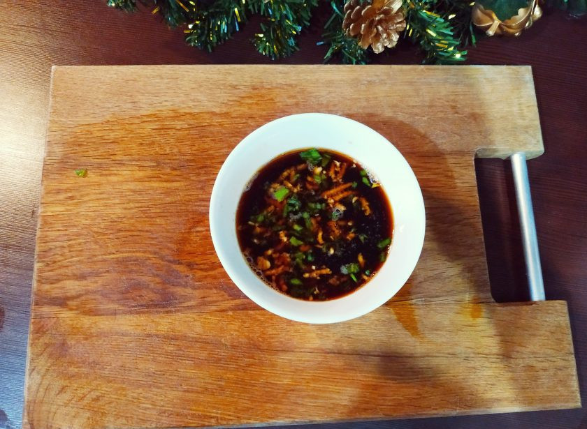 1. Этап. Цзяоцзы: Пока готовятся наши пельмени, можно сделать подходящий китайский соус. Для этого порежьте вторую часть зеленого лука, раздавите зубчик чеснока и немного имбиря, залейте уксусом и соевым соусом в равных частях. Соус готов.