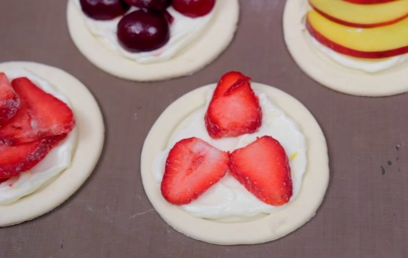 1. Этап. Слоеные пирожки на завтрак: 3. Далее нарежьте фрукты и ягоды на небольшие кусочки и украсьте ими пирожки (у меня это нектарин, клубника и вишня). Слегка взбитым яйцом смажьте края пирожков и присыпьте их сахаром, чтобы потом образовалась хрустящая корочка.