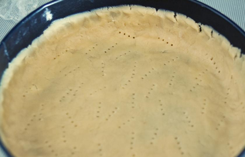 1. Этап. Венесуэльский банановый торт: Тесто достаем из холодильника, раскатываем из него большую лепешку. Берем форму для выпекания (диаметр - около 25 см), смазываем сливочным маслом, выкладываем в него тесто. Вилкой делаем небольшие дырочки в тесте.