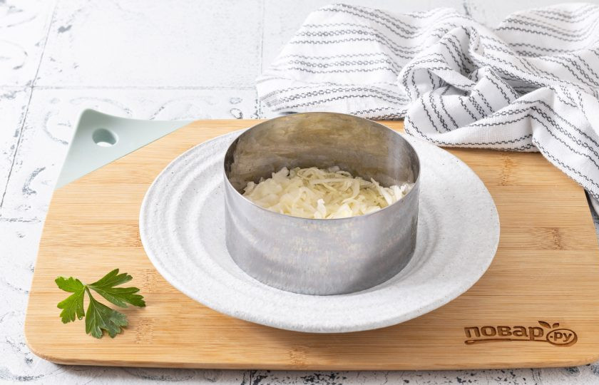 1. Этап. Салат Желание: На дно кольца выложите плотный слой из половины капусты. Подсолите по вкусу.