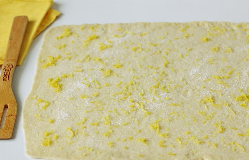 1. Этап. Лимонное печенье на кефире: Раскатайте тесто в форме прямоугольника, толщиной 2-3 мм. на смазанной маслом поверхности. Смажьте тесто растительным маслом, посыпьте сахаром по вкусу и цедрой лимона.