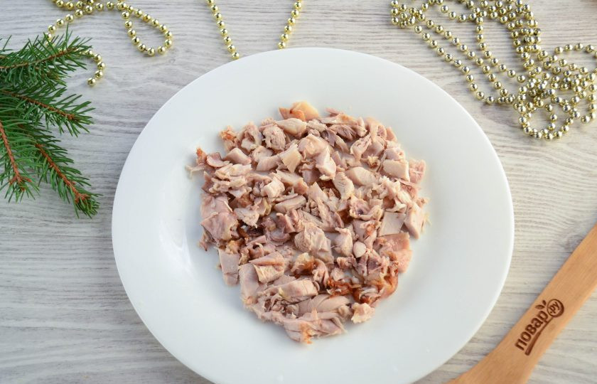 1. Этап. Слоеный салат «Мышка» с грибами и сыром: Начинаем собирать салат. Куриное мясо отделите от кости и измельчите. Кожицу снимите, она нам не понадобится. Выложите куриное мясо на плоскую тарелку, придав форму овала.