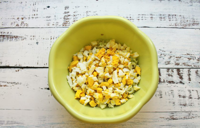 1. Этап. Салат Настроение: Отварные яйца очистите, порежьте кубиком и добавьте в миску с салатом.