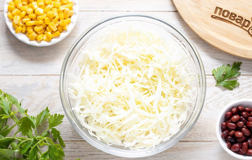 1. Этап. Салат с капустой, фасолью и кукурузой: Капусту тонко нашинкуйте. Немного подсолите и пожмите руками, чтобы она стала мягче.