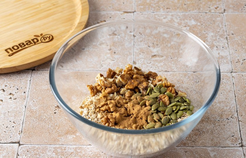 1. Этап. Овсяная гранола с тыквой: Смешайте в большой миске овсяные хлопья, крупно порубленные грецкие орехи и тыквенные семечки. Добавьте корицу и щепотку соли.