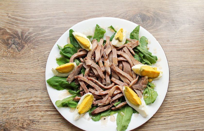 1. Этап. Салат с рукколой и языком: Яйцо очистите и разделите на шесть долек. Выложите яйцо поверх языка и полейте все заправкой.