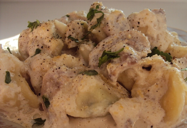 1. Этап. Тортеллини с мясом: Наливаем в кастрюльку воду, когда она закипит, солим ее и выкладываем тортеллини. Пока они варятся, мы займемся соусом. Шампиньоны нарезаем пластинками и обжариваем до испарения жидкости. Сливки варим в кастрюльке на медленном огне в течение 2 минут, а когда они начнут загустевать, добавляем к ним обжаренные грибы и тертый Пармезан. Варить эту смесь, постоянно помешивая, до загустения соуса. Готовые тортеллини выкладываем на порционные тарелки, поливаем соусом, посыпаем перцем и подаем к столу. Приятного всем аппетита!