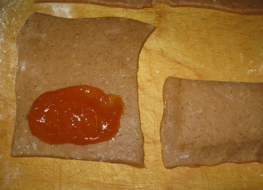 1. Этап. Тульский пряник постный: 4. Стол обильно присыпьте мукой, раскатайте на нем тесто толщиной около 5 мм. Разрежьте пласт теста на квадраты (их должно получиться 8-9 штук). На половину каждого квадрата выложите повидло (распределите его так, чтобы на всех квадратах его было одинаковое количество), заверните вторую половину, чтобы накрыть повидло, и придавите по краям пальцами. Тесто должно очень хорошо склеиваться, так что начинка не вытечет.