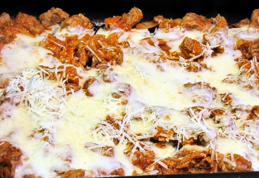 1. Этап. Мусака с бараниной: Теперь наступает время «сборки». Берем форму для запекания, смазываем ее маслом. На дно выкладываем сплошным слоем запеченные ломтики баклажанов. На них — слой мясо-овощной начинки. Заливаем все соусом бешамель, посыпаем тертым сыром. Выкладываем следующий слой баклажанов, следующий слой начинки, снова заливаем соусом и посыпаем сыром. Слоев может быть сколько угодно, все зависит от ваших желаний и глубины формы. Самый верхний слой — баклажаны под соусом и сыром. Приведенные здесь количества ингредиентов позволяют собрать мусаку из трех слоев баклажанов и двух слоев мяса в форме размерами примерно 30 х 20 см. Этого хватит человек на шесть. Ну, или на четверых, но до отвала.