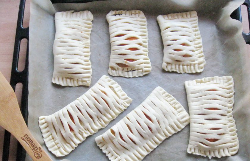 1. Этап. Слойки с творогом и абрикосами: Противень застелите пекарской бумагой или силиконовым ковриком. Выложите слойки.