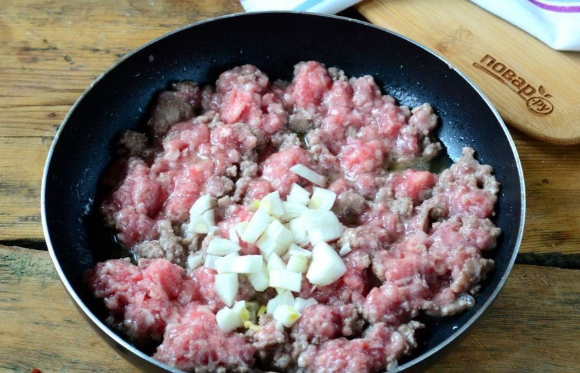 1. Этап. Пирог из спагетти под сыром: Фарш выложите в сковороду с разогретым растительным маслом и жарьте на большом огне, часто помешивая, чтобы фарш слегка подрумянился и пустил сок. Затем добавьте измельченную луковицу, соль и перец, готовьте еще несколько минут.