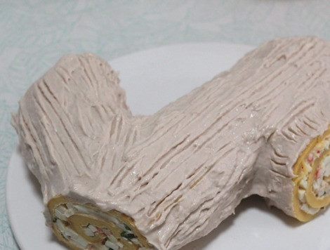 1. Этап. Рулет закусочный Рождественское полено: Рулет оформить в виде полена - рулет порезать на 3 части - самую длинную, среднюю и короткую. Короткую и среднюю приложить к бокам самой длинной части. Нанести покрытие. Провести по поверхности зубчиками вилки. По желанию украсить молотыми фисташками. Поставить в холодильник минимум на пару часов.