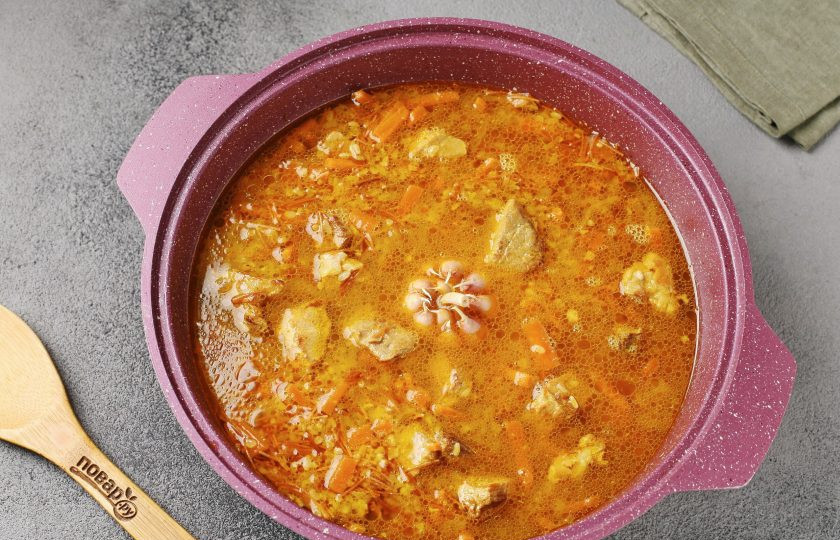 1. Этап. Плов с булгуром и жареной вермишелью: Влейте кипяток. Вода должна быть выше уровня примерно на 1,5-2 см. По центру вставьте очищенную от верхней шелухи головку чеснока. Накройте крышкой, доведите до кипения, затем убавьте огонь до минимального и готовьте 20-25 минут.