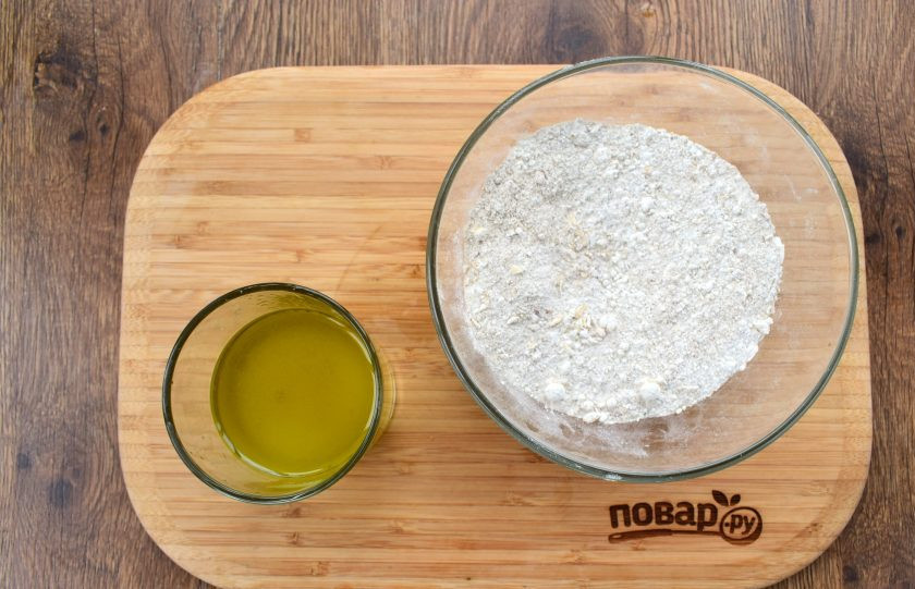 1. Этап. Ржаное пирожное постное: Овсяные хлопья слегка измельчите: потрите между ладонями. В глубокой миске соедините сухие ингредиенты и перемешайте. Масло соедините с кипятком, перемешайте.