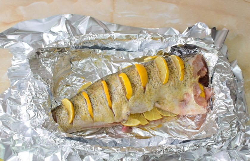 1. Этап. Судак с лимоном в фольге: Форму для запекания застелите в несколько слоев фольги и выложите рыбу. А надрезы вставьте ломтики лимона.