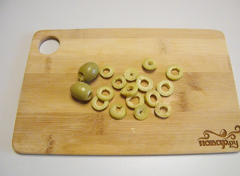 1. Этап. Салат с кальмарами самый вкусный: Оливки без косточек порежьте колечками. Зеленые оливки можно заменить на черные, с ними салат не менее вкусный получится.