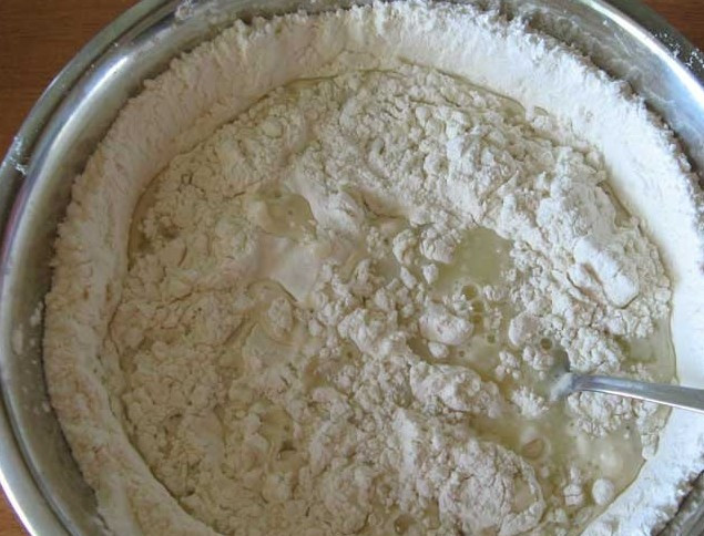 1. Этап. Вареники на кефире: В это углубление вливаем кефирную массу, начинаем все перемешивать викой.