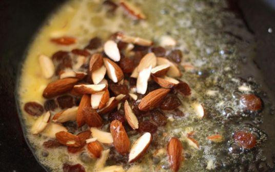 1. Этап. Халва из манки: В сковородке нагреть две ложки сливочного масла. В масле обжарить рубленные орехи и изюм. Готовые орехи и изюм выложить на тарелочку.